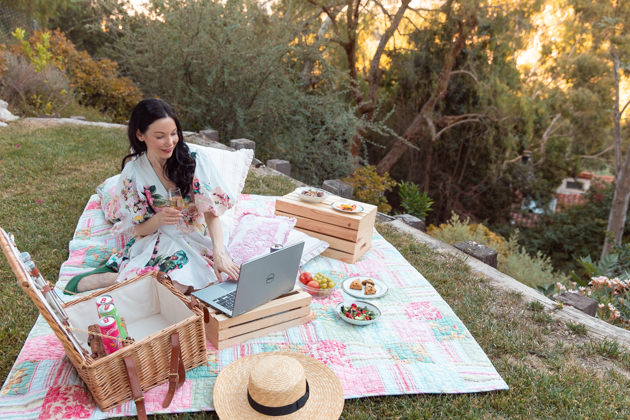 How to Host A Virtual Picnic, Quarantine Life, Things to do during Quarantine Outside, Virtual Picnic Menu, Things to do in your backyard #VirtualPicnic #SummerPicnic #QuarantineActivities Hemant and Nandita Dress, No-Mayo Potato Salad, Smoked Salmon, Gluten-Free Chocolate Chip Scones, Casa Luigi Prosecco, Pretty Little Shoppers Blog | Virtual Picnic by popular L.A. lifestyle blog, Pretty Little Shoppers: image of a woman wearing a Teien Mini Dress HEMANT AND NANDITA brand: HEMANT AND NANDITA and Amazon Lack of Color Women's The Spencer Boater Hat and sitting next to a wicker picnic basket, wooden crates, plates of food, and some Casa Luigi sparkling wine on a patchwork quilt outside. 