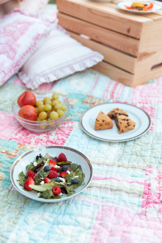 Summer Salad with Berries and Goat Cheese | Virtual Picnic by popular L.A. lifestyle blog, Pretty Little Shoppers: image of a bowl of fruit, gluten-free chocolate chip scones, and fruit salad on a patchwork quilt. 