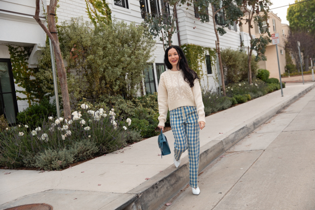 How to Wear Gingham for Fall, What to wear Fall 2020, Fall Transitional Look, Capulet Gingham Pants, White Cable knit Sweater, Joseph and Stacey Bag, Los Angeles Fashion Blogger, Pretty Little Shoppers Blog #Gingham #GinghamStyle | Fall Clothing by popular L.A. fashion blog, Pretty Little Shoppers: image of a woman walking down a sidewalk and wearing a pair of Capulet gingham pants, J.O.A sweater, Aqua mules and carrying a Joseph and Stacey bag.  