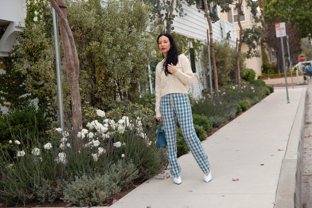 How to Wear Gingham for Fall, What to wear Fall 2020, Fall Transitional Look, Capulet Gingham Pants, White Cable knit Sweater, Joseph and Stacey Bag, Los Angeles Fashion Blogger, Pretty Little Shoppers Blog #Gingham #GinghamStyle | Fall Clothing by popular L.A. fashion blog, Pretty Little Shoppers: image of a woman walking down a sidewalk and wearing a pair of Capulet gingham pants, J.O.A sweater, Aqua mules and carrying a Joseph and Stacey bag.  