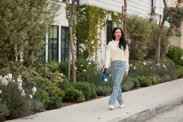 How to Wear Gingham for Fall, What to wear Fall 2020, Fall Transitional Look, Capulet Gingham Pants, White Cable knit Sweater, Joseph and Stacey Bag, Los Angeles Fashion Blogger, Pretty Little Shoppers Blog #Gingham #GinghamStyle | Fall Clothing by popular L.A. fashion blog, Pretty Little Shoppers: image of a woman walking down a sidewalk and wearing a pair of Capulet gingham pants, J.O.A sweater, Aqua mules and carrying a Joseph and Stacey bag.  