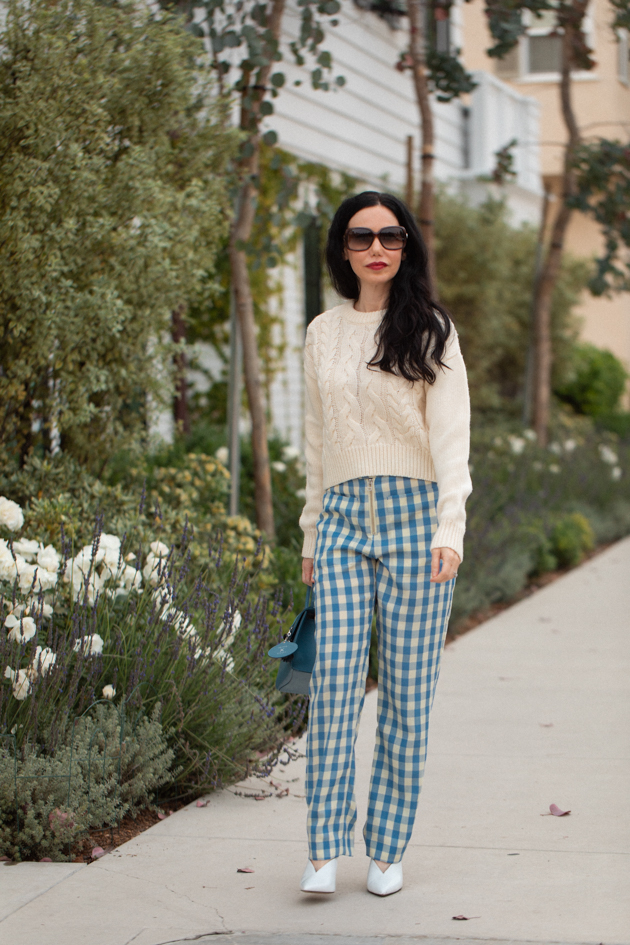 How to Wear Gingham for Fall, What to wear Fall 2020, Fall Transitional Look, Capulet Gingham Pants, White Cable knit Sweater, Joseph and Stacey Bag, Los Angeles Fashion Blogger, Pretty Little Shoppers Blog #Gingham #GinghamStyle | Fall Clothing by popular L.A. fashion blog, Pretty Little Shoppers: image of a woman walking down a sidewalk and wearing a pair of Capulet gingham pants, J.O.A sweater, Aqua mules and carrying a Joseph and Stacey bag.  