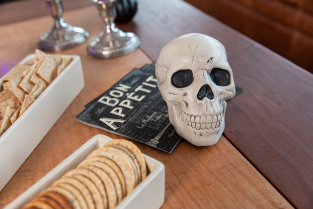 Halloween Cheese Platter and Candy Buffet, Celebrating Halloween In My New House, Halloween Ideas, How to Celebrate Halloween at Home, Halloween Ideas during Covid-19 Quarantine, Los Angeles Lifestyle Blogger, Pretty Little Shoppers Blog, Halloween Decorations #Halloween2020 #HalloweenCheesePlatter |Cheese Platter by popular LA lifestyle blog, Pretty Little Shoppers: image of a skull decoration next to two white ceramic dishes filled with crackers. 