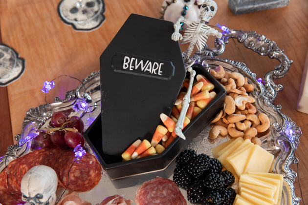 Halloween Cheese Platter and Candy Buffet, Celebrating Halloween In My New House, Halloween Ideas, How to Celebrate Halloween at Home, Halloween Ideas during Covid-19 Quarantine, Los Angeles Lifestyle Blogger, Pretty Little Shoppers Blog, Halloween Decorations #Halloween2020 #HalloweenCheesePlatter |Cheese Platter by popular LA lifestyle blog, Pretty Little Shoppers: image of a coffin shaped candy dish filled with candy corn candy on a meat and cheese platter. 