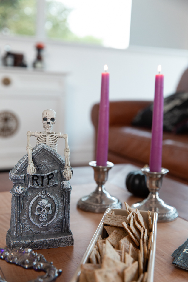 Celebrating Halloween In My New House, Halloween Ideas, How to Celebrate Halloween at Home, Halloween Ideas during Covid-19 Quarantine, Los Angeles Lifestyle Blogger, Pretty Little Shoppers Blog, Halloween Decorations #Halloween2020 |Cheese Platter by popular LA lifestyle blog, Pretty Little Shoppers: image of purple candle sticks in silver candle stick holders, skeleton and tombstone decor and a dish filled with crackers. 