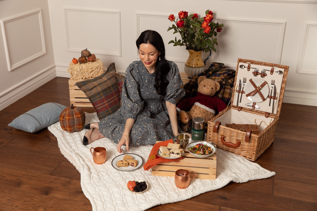 Indoor Fall Picnic, Fall Harvest Picnic Menu, Doen Fawn Dress, Lisa Valerie Morgan, Pretty Little Shoppers Blog, Los Angeles Lifestyle Blogger, How to Celebrate Thanksgiving During Quarantine, Holiday Ideas During Covid Quarantine #IndoorPicnic #ThanksgivingIdeas |Fall Picnic by popular LA lifestyle blog, Pretty Little Shoppers: image of a woman sitting on a knit cream blanket and having an indoor picnic. 