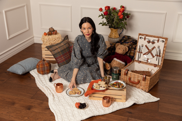 Indoor Fall Picnic, Fall Harvest Picnic Menu, Doen Fawn Dress, Lisa Valerie Morgan, Pretty Little Shoppers Blog, Los Angeles Lifestyle Blogger, How to Celebrate Thanksgiving During Quarantine, Holiday Ideas During Covid Quarantine #IndoorPicnic #ThanksgivingIdeas |Fall Picnic by popular LA lifestyle blog, Pretty Little Shoppers: image of a woman sitting on a knit cream blanket and having an indoor picnic. 