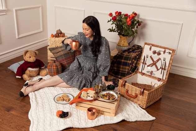 Indoor Fall Picnic, Fall Harvest Picnic Menu, Doen Fawn Dress, Lisa Valerie Morgan, Pretty Little Shoppers Blog, Los Angeles Lifestyle Blogger, How to Celebrate Thanksgiving During Quarantine, Holiday Ideas During Covid Quarantine #IndoorPicnic #ThanksgivingIdeas | Fall Picnic by popular LA lifestyle blog, Pretty Little Shoppers: image of a woman sitting on a knit cream blanket and having an indoor picnic. 