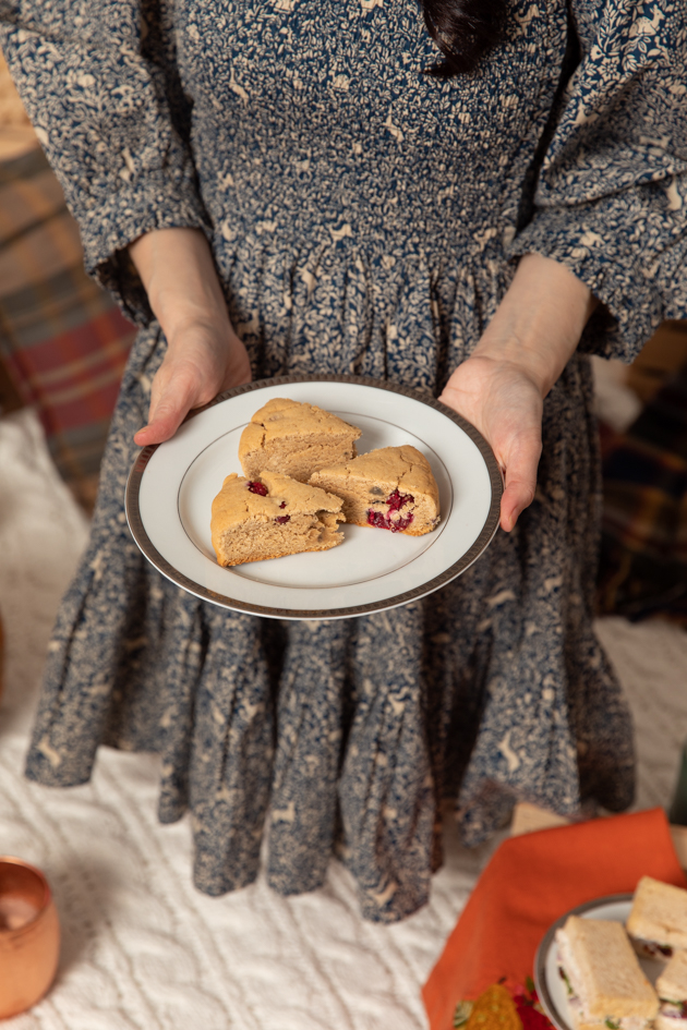 Gluten-free Cranberry Scones |Fall Picnic by popular LA lifestyle blog, Pretty Little Shoppers: image of a woman holding a plate of gluten-free cranberry scones. 