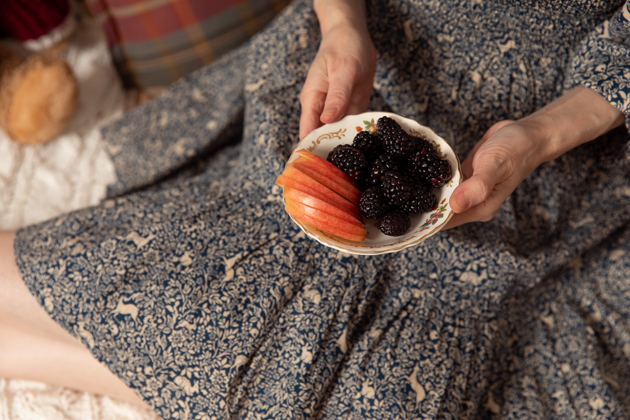 | Fall Picnic by popular LA lifestyle blog, Pretty Little Shoppers: image of a woman holding a bowl of sliced apples and blackberries. 