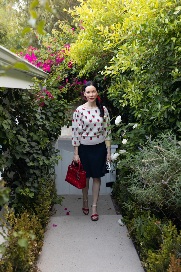 Fall Transitional Look, Waiting for Election Results, Red White and Blue Outfit, LoveShackFancy Strawberry Sweater, Tommy Hilfiger Collection Skirt, Italic Cateye Sunglasses, Lady Dior Bag, Classic and Feminine Style, What to Wear for Fall, Fall in Los Angeles, Preppy Style Los Angeles Lifestyle Blogger, Pretty Little Shoppers Blog #FallTransitionalLook #PreppyStyle |Fall Clothing by popular L.A. fashion blog, Pretty Little Shoppers: image of a woman wearing a strawberry Net-A-Porter sweater, Dior purse, Tommy Hilfiger skirt, plaid block heel sandals, and Italic sunglasses.