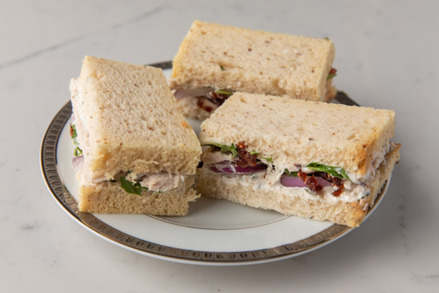 Gluten-free Sandwich Ideas for a Holiday High Tea Party |Turkey Cranberry Sandwich by popular LA lifestyle blog, Pretty Little Shoppers: image of some gluten and dairy free turkey cranberry sandwiches on a white plate. 