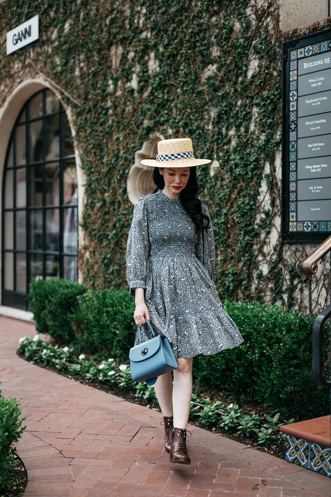 Cottagecore, Romantic Dress, Doen Fawn dress, Lack of Color Boater Hat, Sezane Booties, Joseph and Stacey bag, Parisian Chic Style |  Romantic Dress by popular Dallas fashion blog, Pretty Little Shoppers: image of a woman walking on a brick pathway next to a building covered in ivy and wearing a Doen Leda fawn dress, Lack of Color straw boater hat, and Suzanne booties.