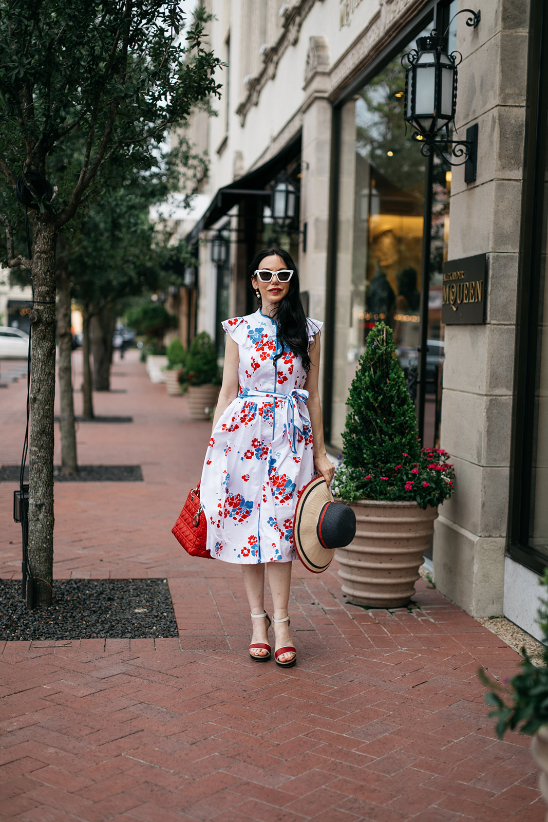Brooks Brothers Shirt Dress, Tommy Hilfiger Sunhat and Sandals, Lady Dior Bag, Dallas Fashion Blogger | Brooks Brothers Shirt Dress by popular Dallas fashion blog, Pretty Little Shoppers: image of a woman walking in  Highland Park Village and wearing a red, whites and blue Brooks Brothers shirt dress, white frame sunglasses, and holding a red and black stripe straw hat. 