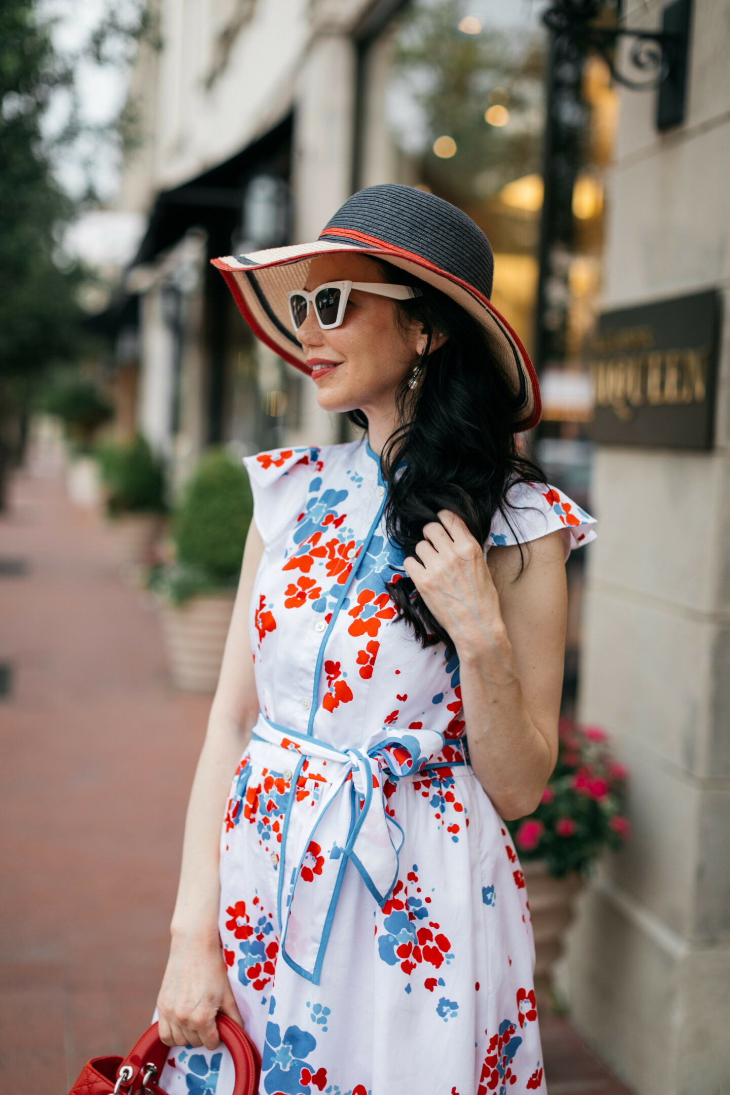 Brooks Brothers Shirt Dress, Tommy Hilfiger Sunhat, Italic Cateye Sunglasses | Brooks Brothers Shirt Dress by popular Dallas fashion blog, Pretty Little Shoppers: image of a woman walking in  Highland Park Village and wearing a red, whites and blue Brooks Brothers shirt dress, white frame sunglasses, and wearing a red and black stripe straw hat while holding a red handbag. 