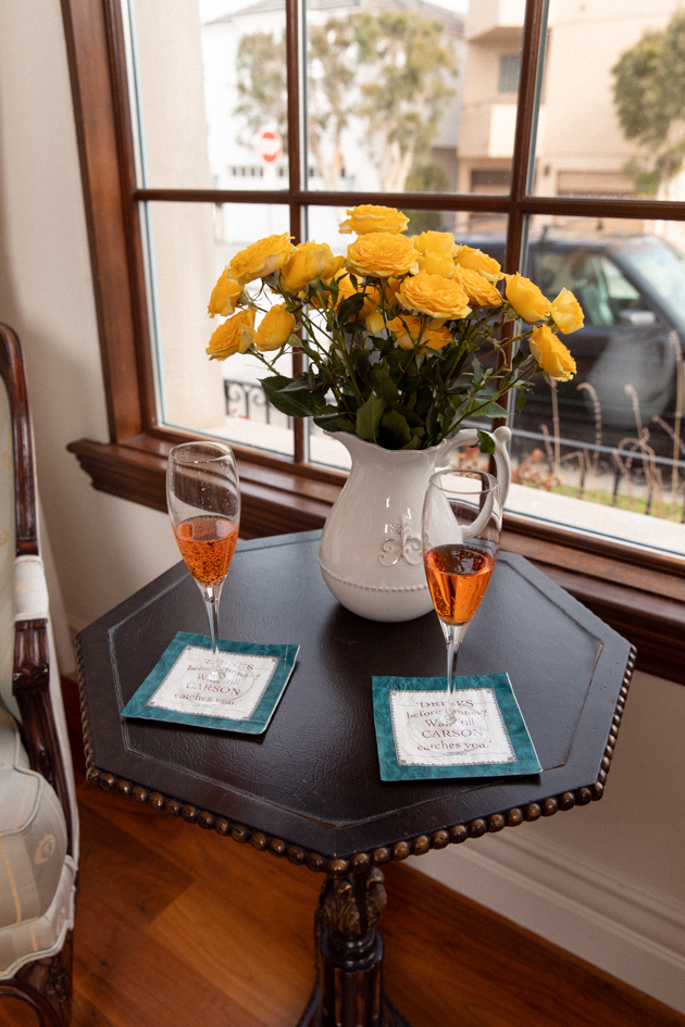 Casa Luigi Prosecco served in Champagne Flutes with Downton Abbey Cocktail Napkins | Online Vintage Clothing by popular Dallas fashion blog, Pretty Little Shoppers: image of two wine flutes next to a vase of yellow roses. 